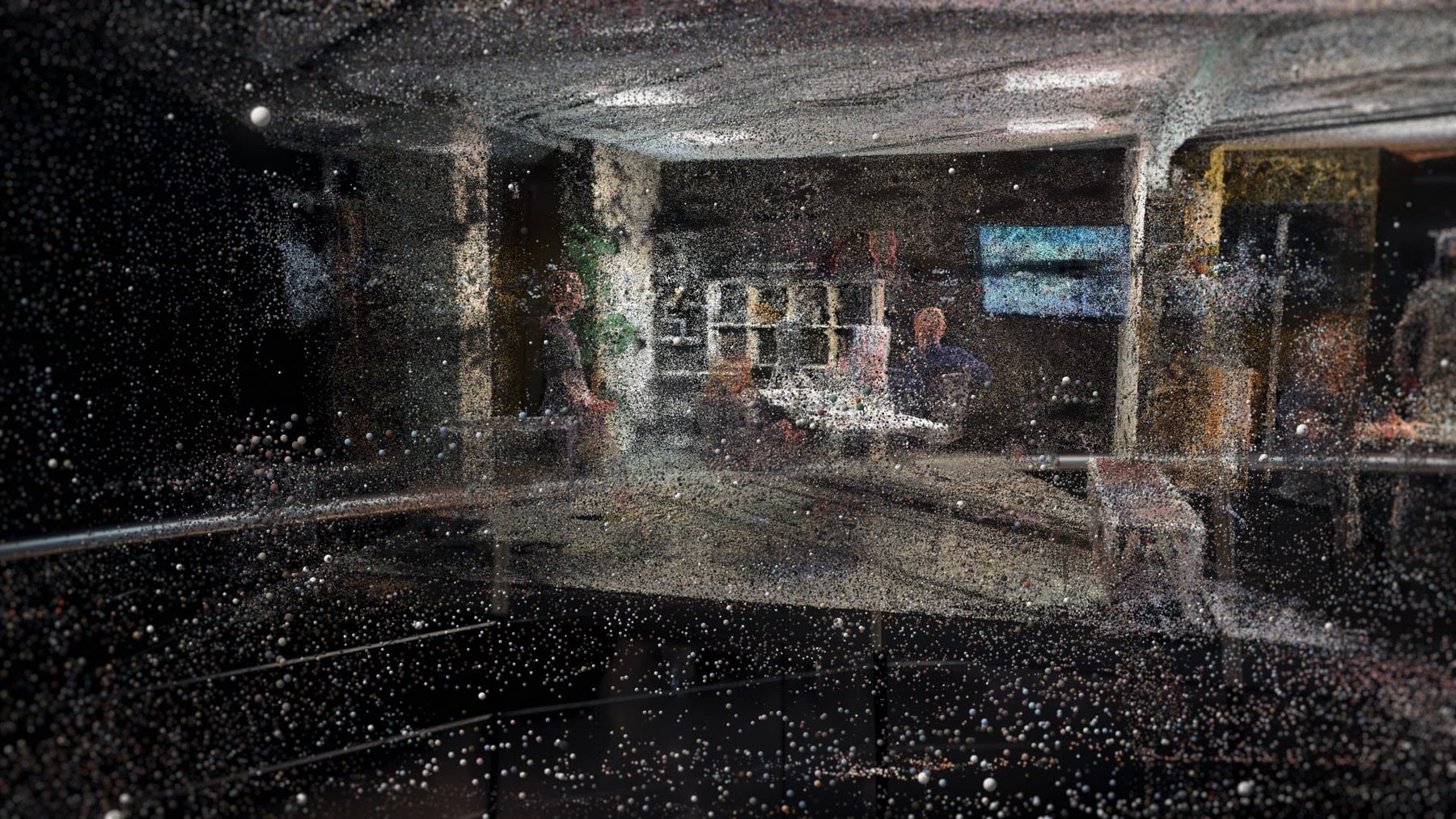 An office half-dissolved: grey particles on the left, the real room in colour beginning to show on the right.